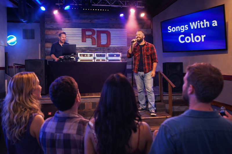 Karaoke singer and host in front of an audience, with a screen announcing Songs With a Color