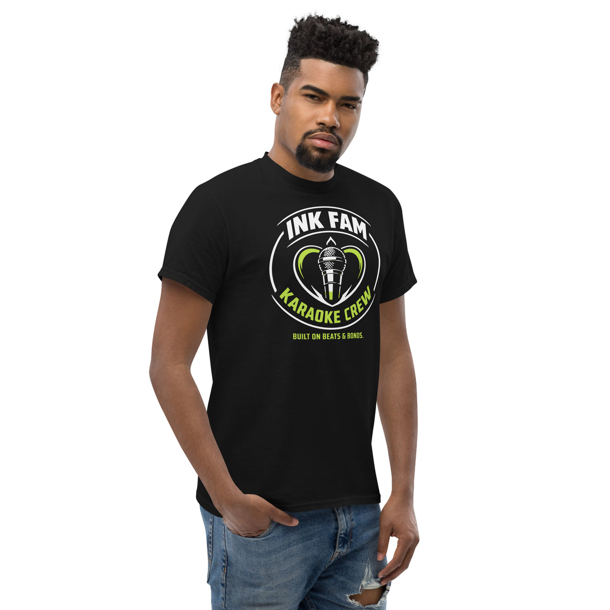 Black classic T-shirt, right-front angled view, featuring DJ Ink Fam green-and-white circular microphone badge.