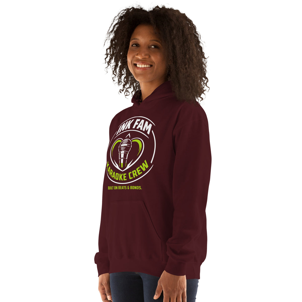 Maroon pullover hoodie, left-front angled view, featuring the green-and-white circular DJ Ink Fam microphone badge.