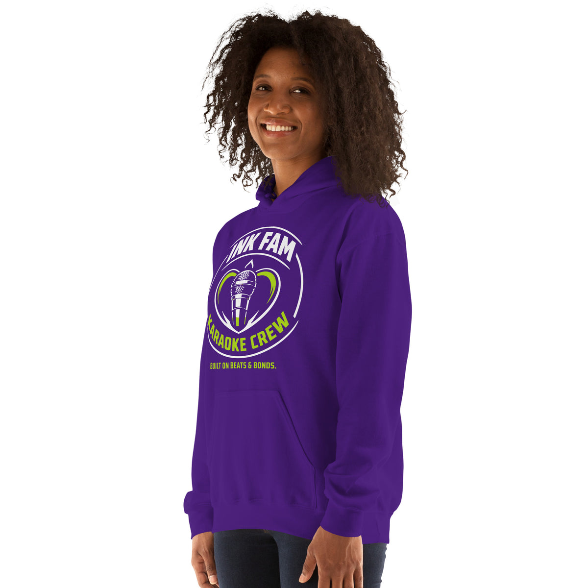 Purple pullover hoodie, left-front angled view, featuring the green-and-white circular DJ Ink Fam microphone badge.