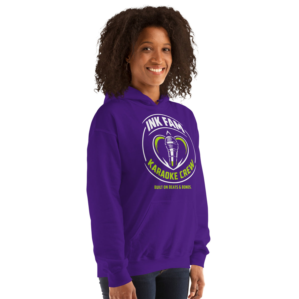 Purple pullover hoodie, right-front angled view, featuring the green-and-white circular DJ Ink Fam microphone badge.
