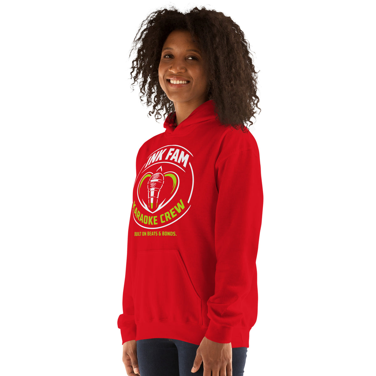 Red pullover hoodie, left-front angled view, featuring the green-and-white circular DJ Ink Fam microphone badge.