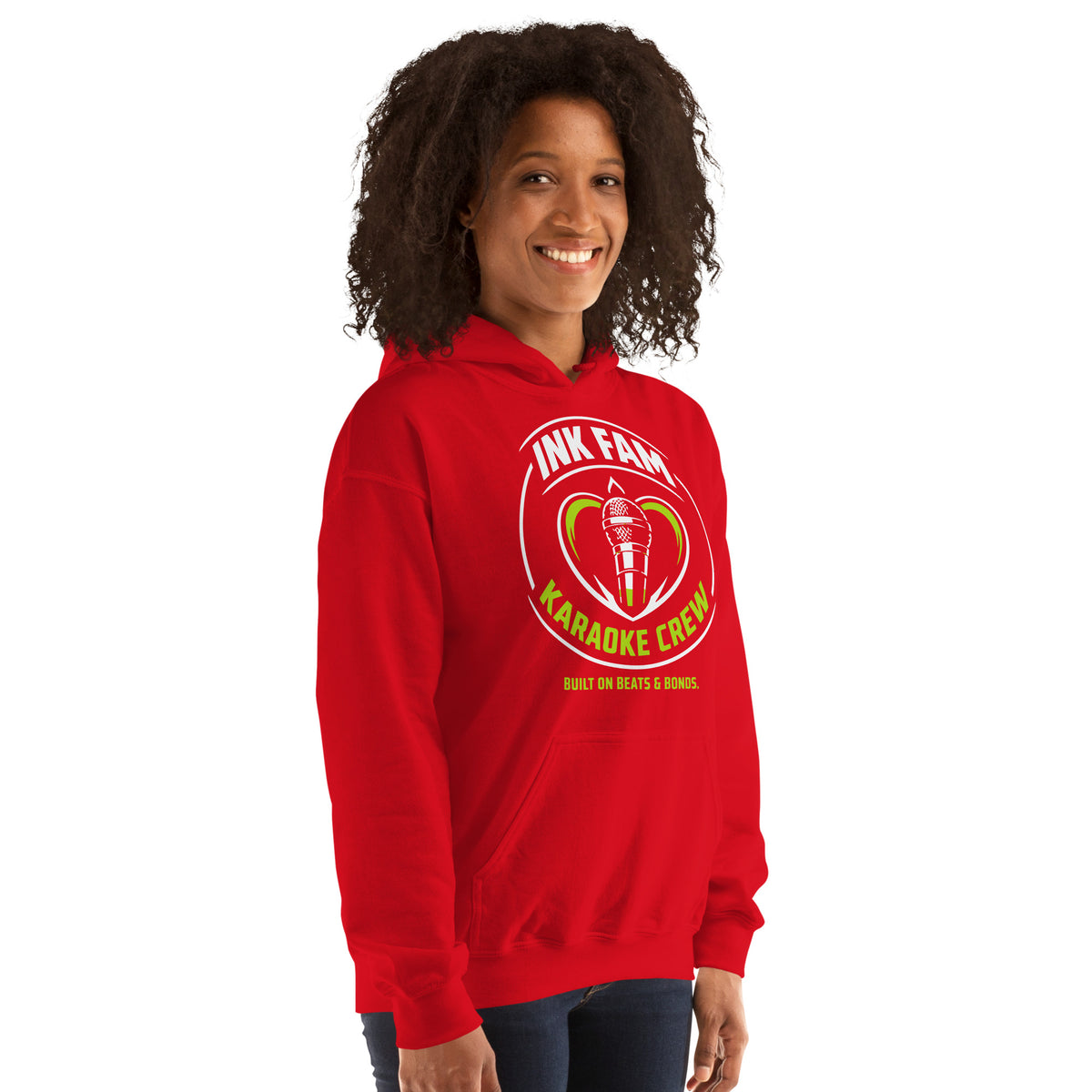Red pullover hoodie, right-front angled view, featuring the green-and-white circular DJ Ink Fam microphone badge.