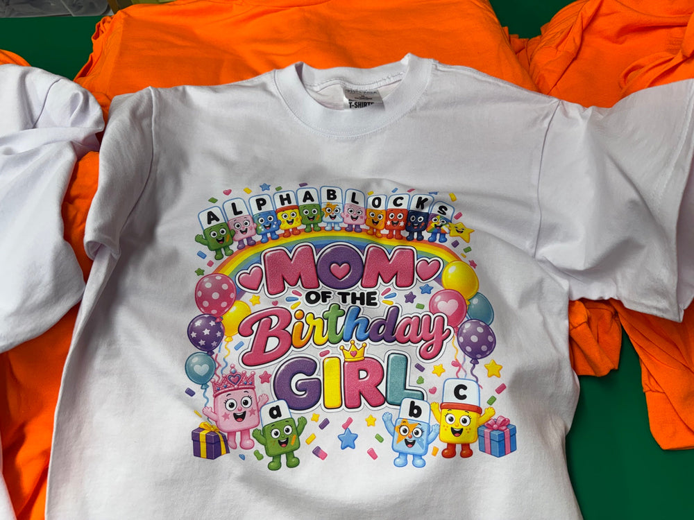 White Mom of the Birthday Girl T-shirt printed by Minty Tees, with colorful alphabet characters, rainbow lettering, balloons and confetti.