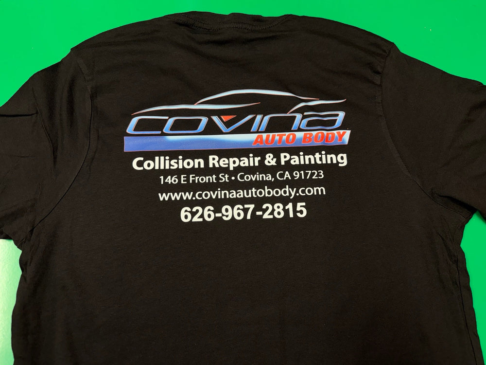 Back of a black Covina Auto Body T-shirt with a large blue-and-red logo and white collision repair and painting contact details.