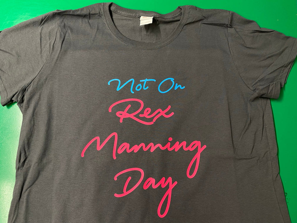 Dark gray T-shirt with Not On in blue script and Rex Manning Day in bright pink script.