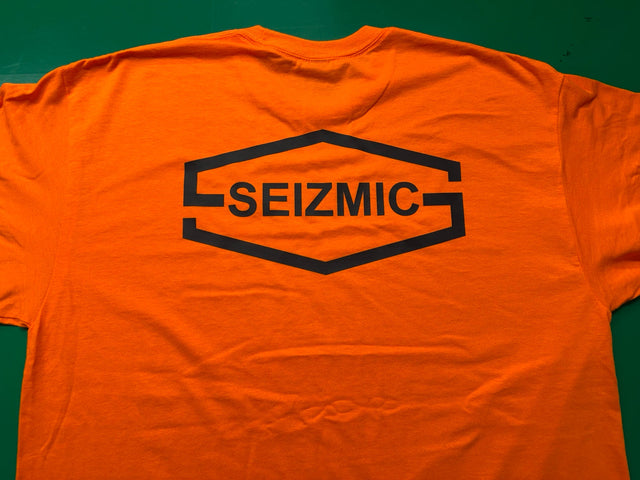 Seizmic’s black company logo printed on the back of a bright orange shirt by Minty Tees.